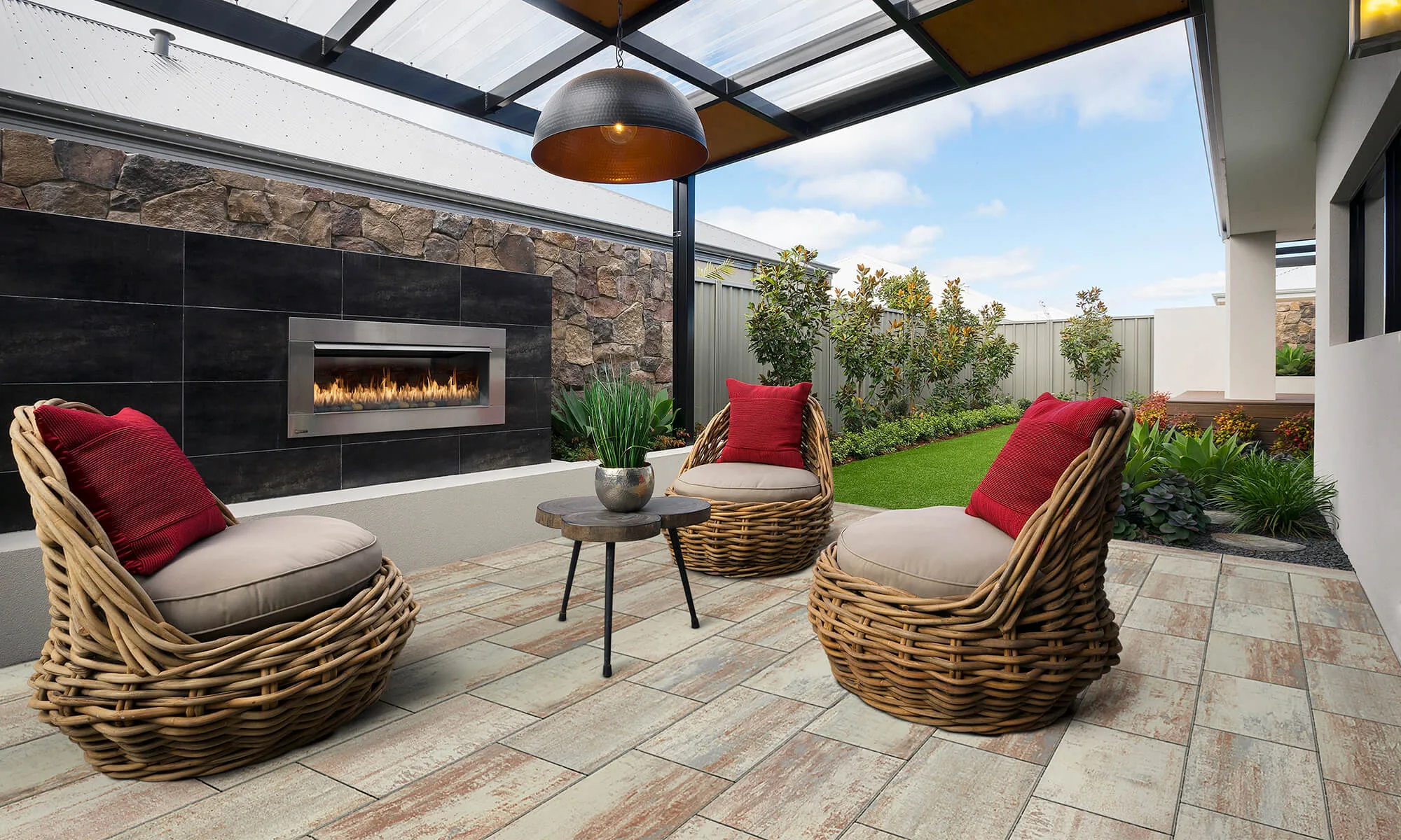 Covered patio with outdoor fireplace, wicker chairs and timber-look paving